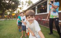 Children enjoy a tug-of-war game outdoors, celebrating teamwork and fun in a garden.